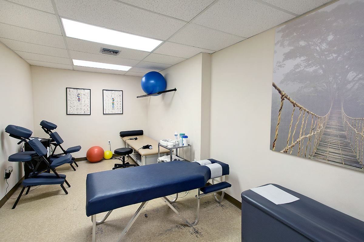 Woman stretching with therapist assisting. Therapy room, beige walls, natural light.