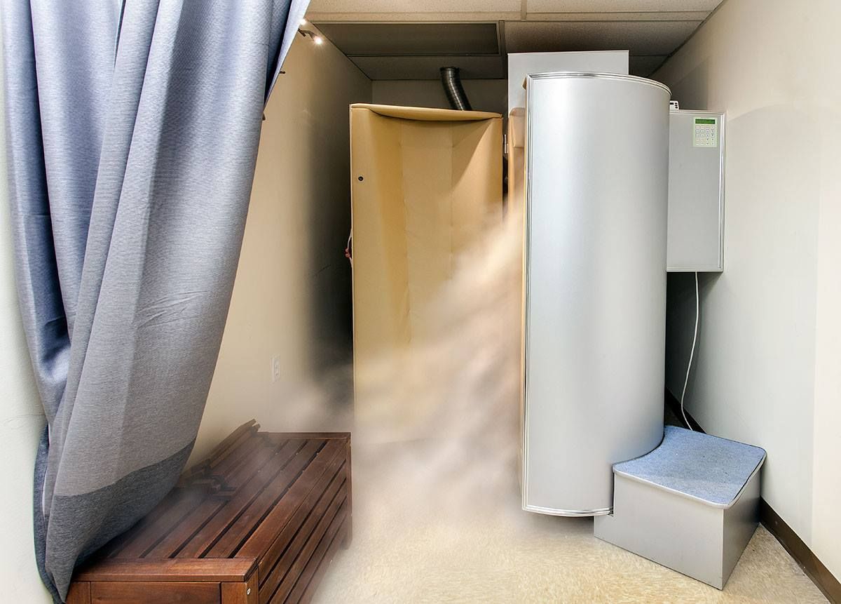 Woman receiving facial treatment; technician using jade roller.