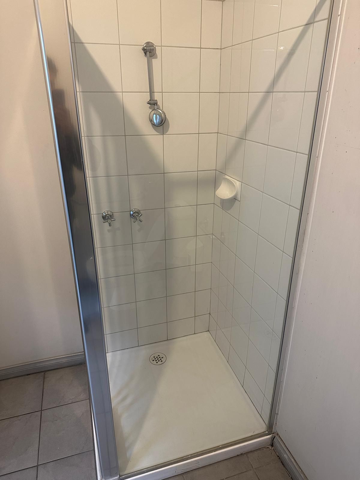 A shower stall with a glass door and a shower head in a bathroom.