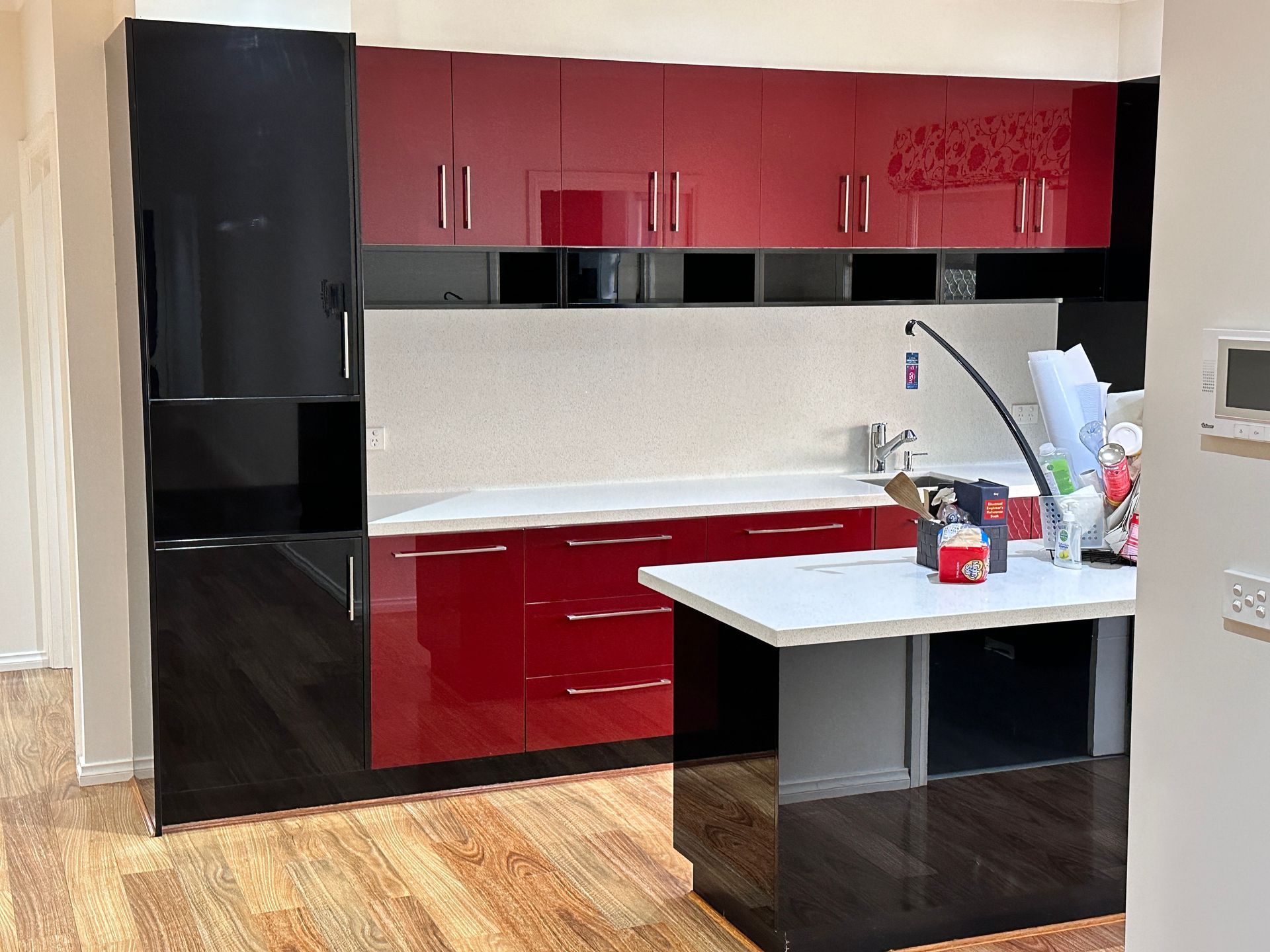 A kitchen with red and black cabinets and a white counter top.