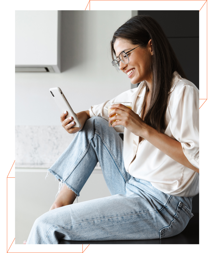 A woman is sitting on the floor using a tablet and drinking coffee.