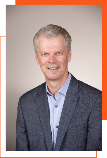 A man in a suit and blue shirt is smiling for the camera