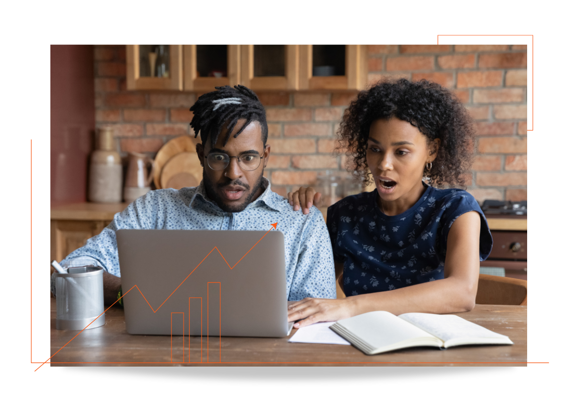 A man and a woman are sitting at a table looking at a laptop computer.