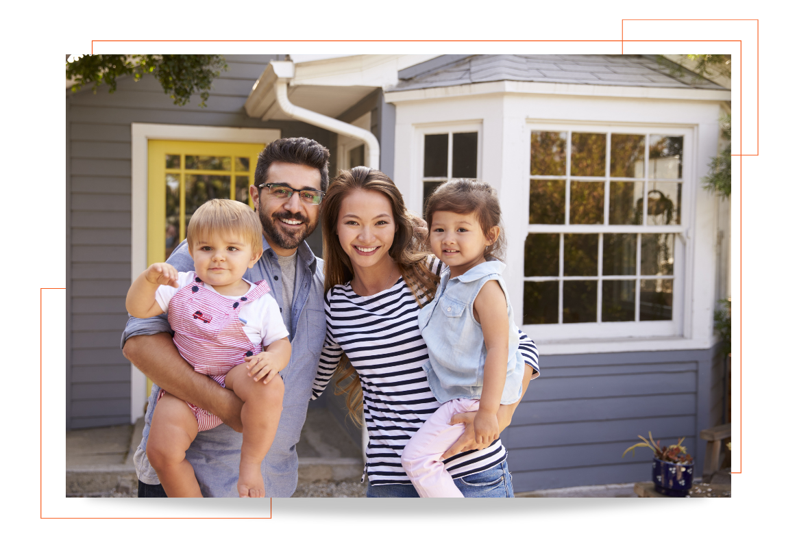 A family is posing for a picture in front of their new home.