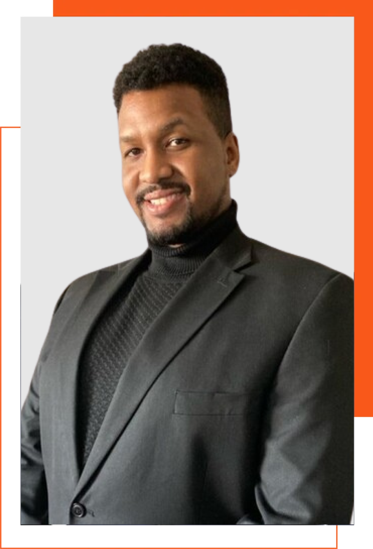 A man in a suit and turtleneck is smiling for the camera.