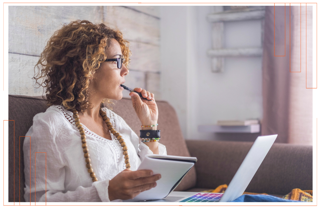 A woman is sitting on a couch using a laptop computer.