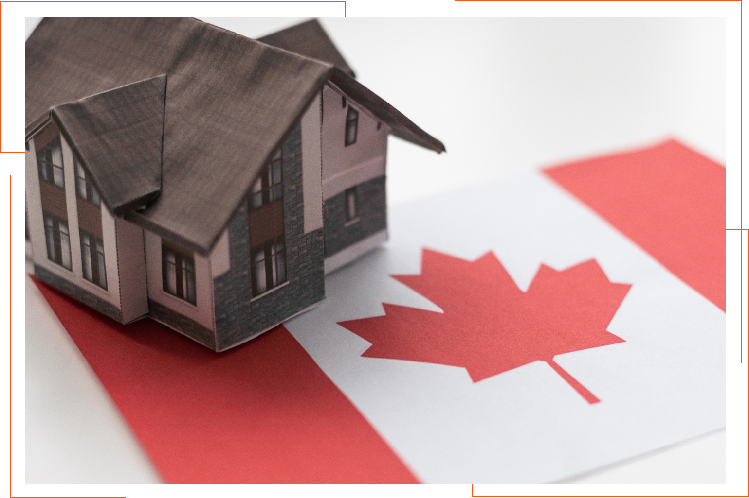 A small house is sitting on top of a canadian flag