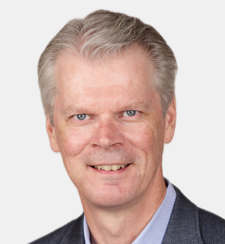 A man in a suit and blue shirt is smiling for the camera.