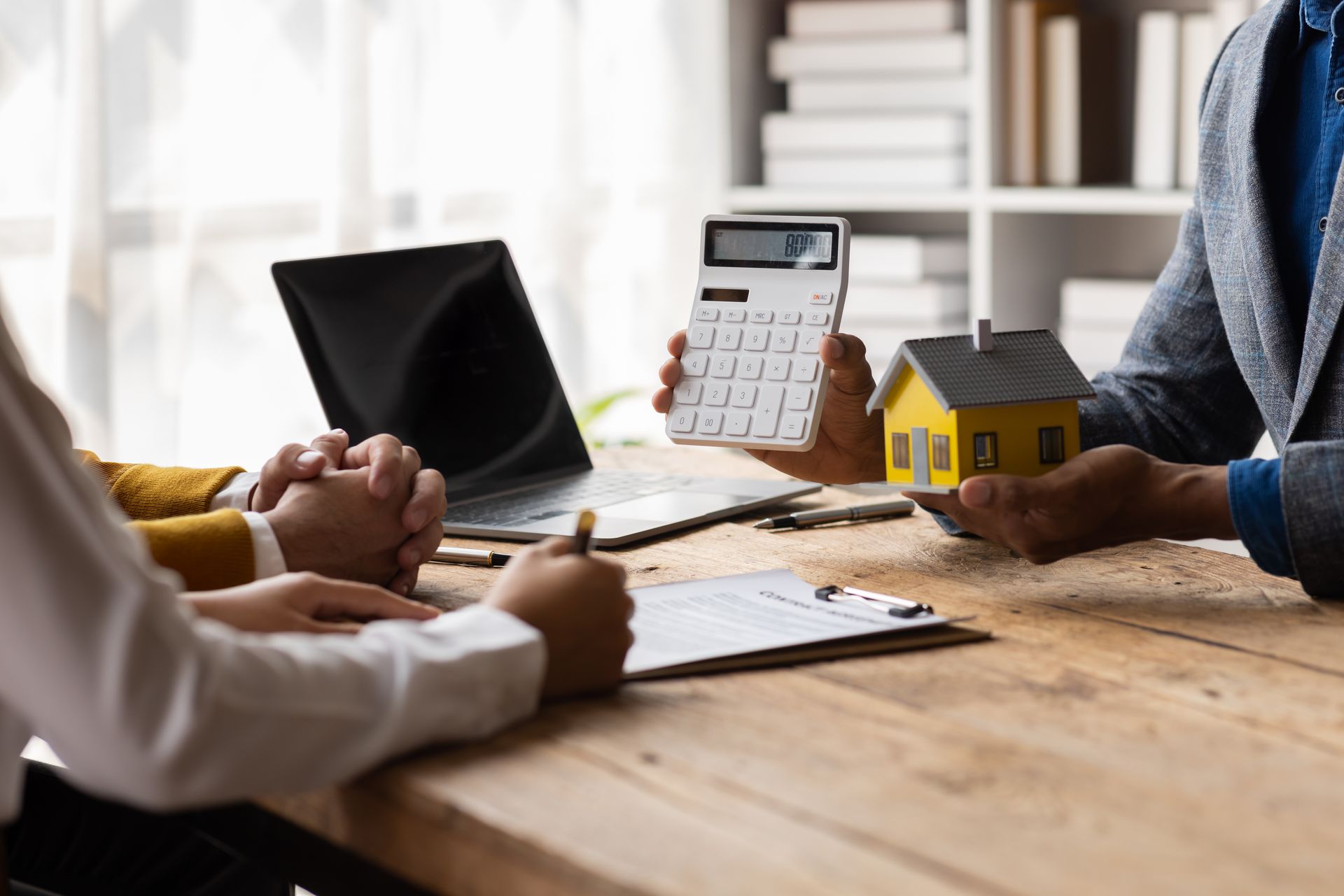 A man is holding a calculator and a model house.