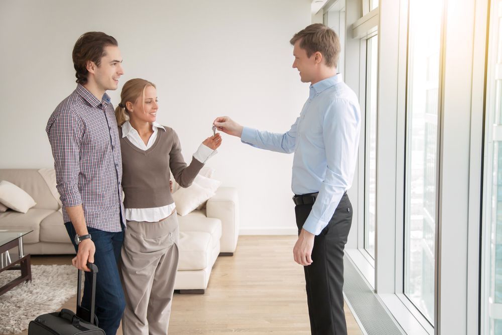 A man is giving keys to a woman in a living room.