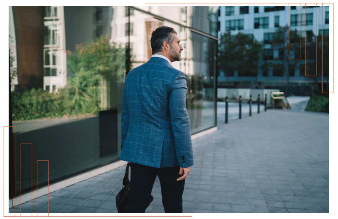 A man in a blue jacket is walking down a sidewalk.