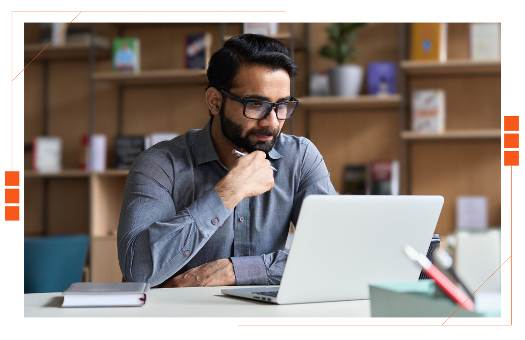 A man is sitting at a desk using a laptop computer.