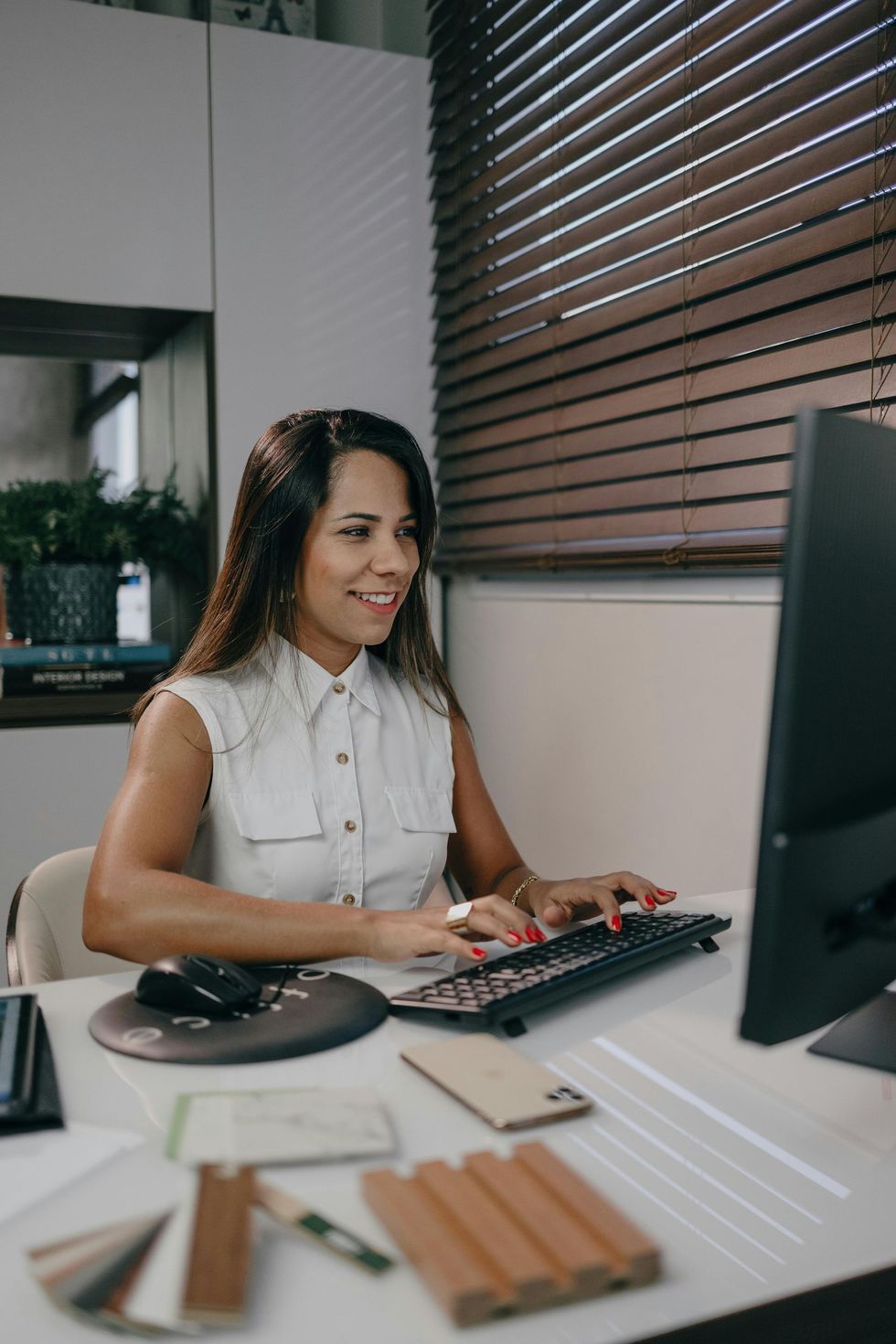 A woman is sitting at a desk in front of a computer.