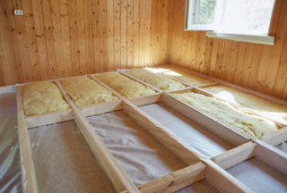 A wooden floor is being insulated in a wooden house.