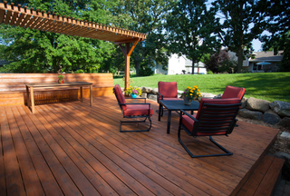 A wooden deck with chairs and a table under a pergola