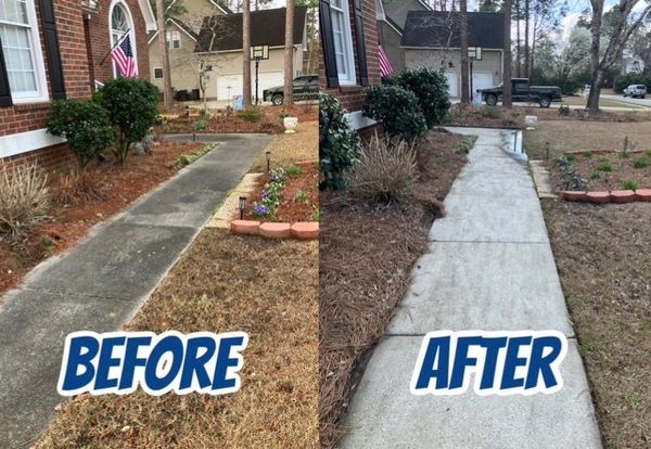 A person in blue overalls pressure washes a yellow and gray brick patio.