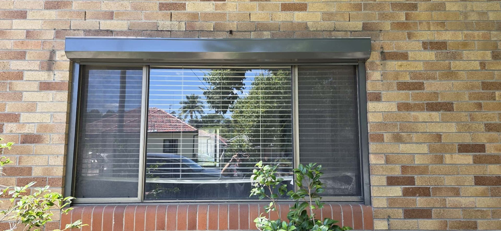 Modern gray living room with a couch, TV, and large windows.