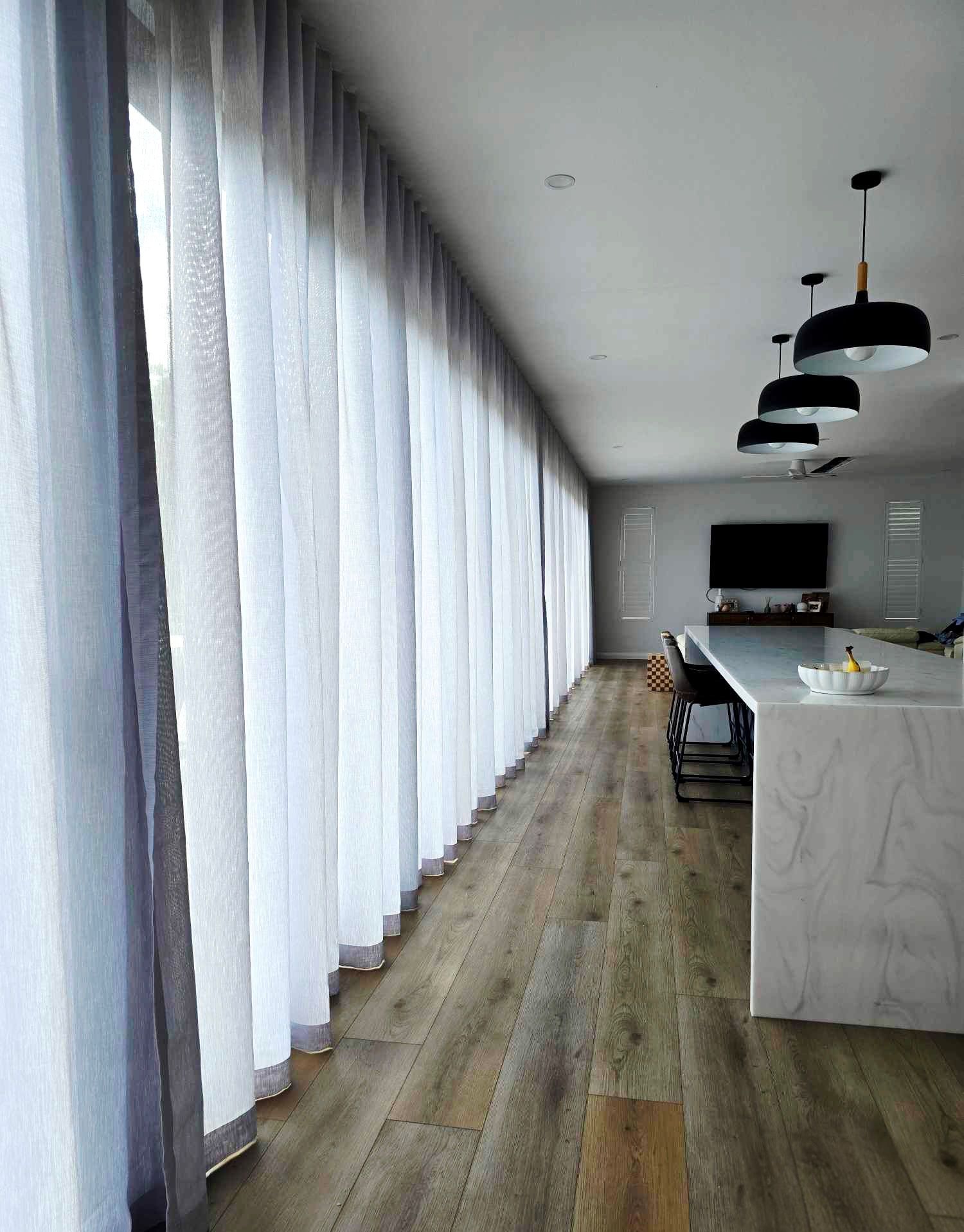 Close-up of vertical, textured gray curtains with subtle shadow and light.