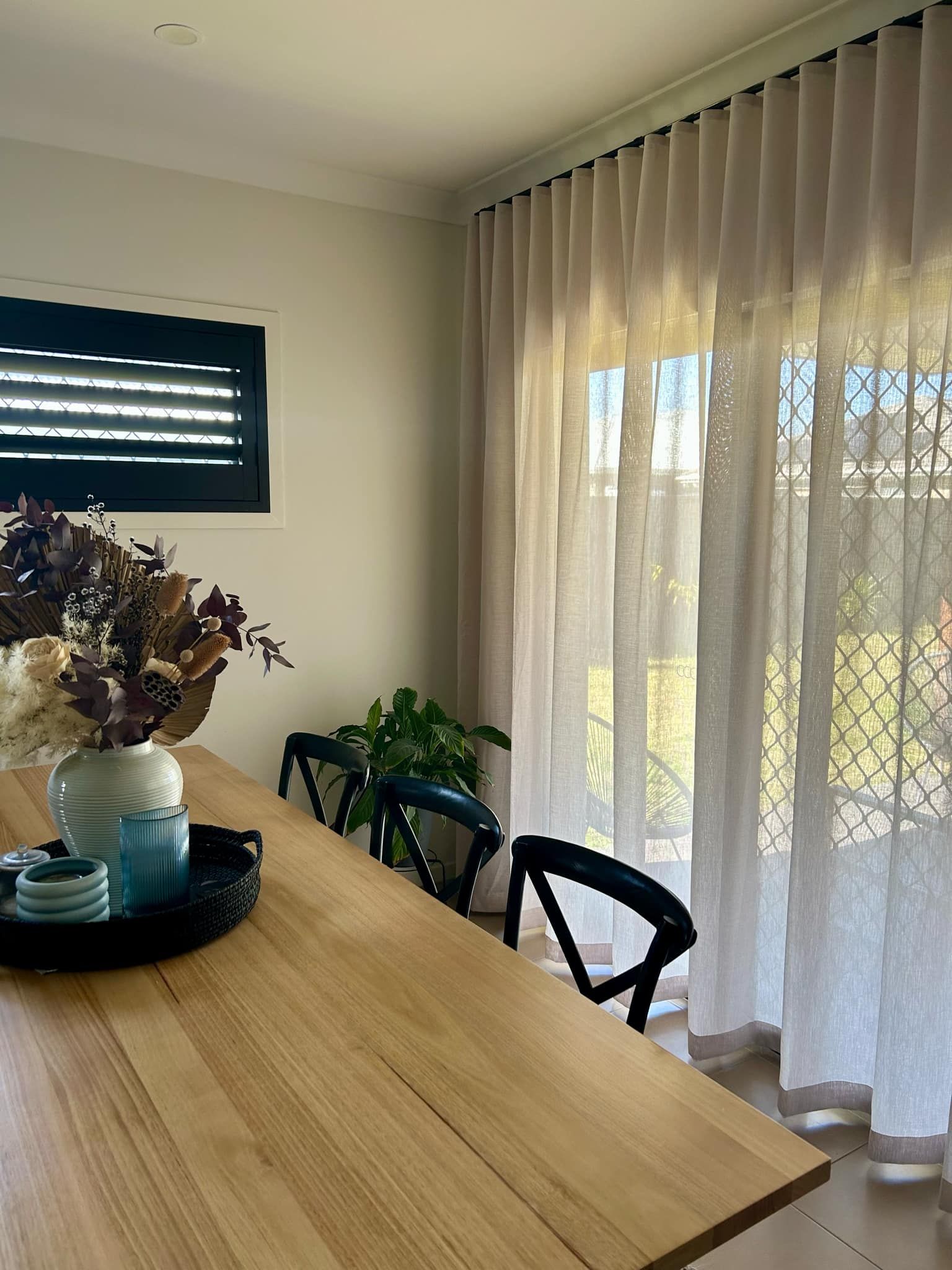 Cozy room with beige curtains, chaise lounge, and wooden floor. Sunlight streams through a window.