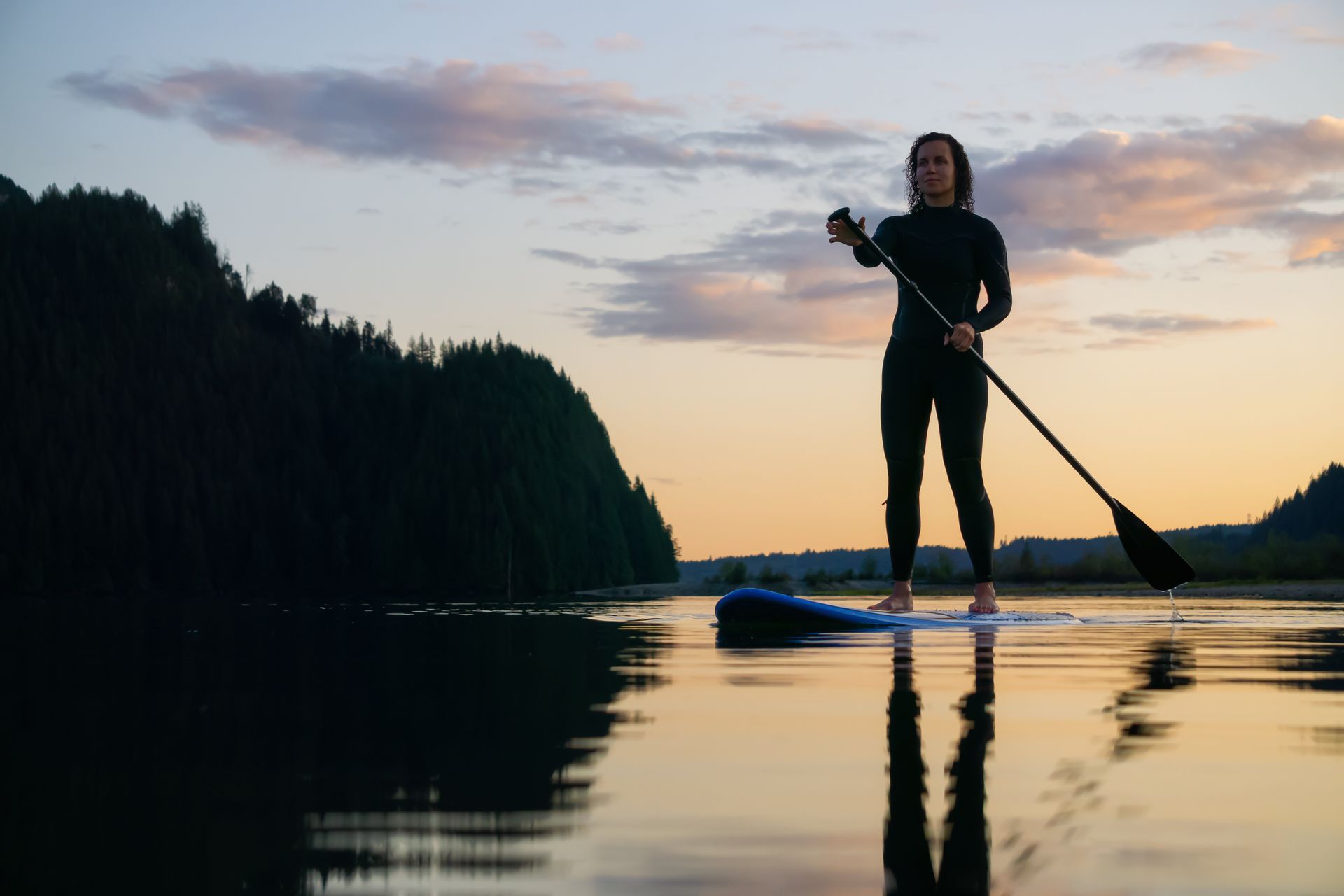 A woman stands on a paddleboard rental in Vermont