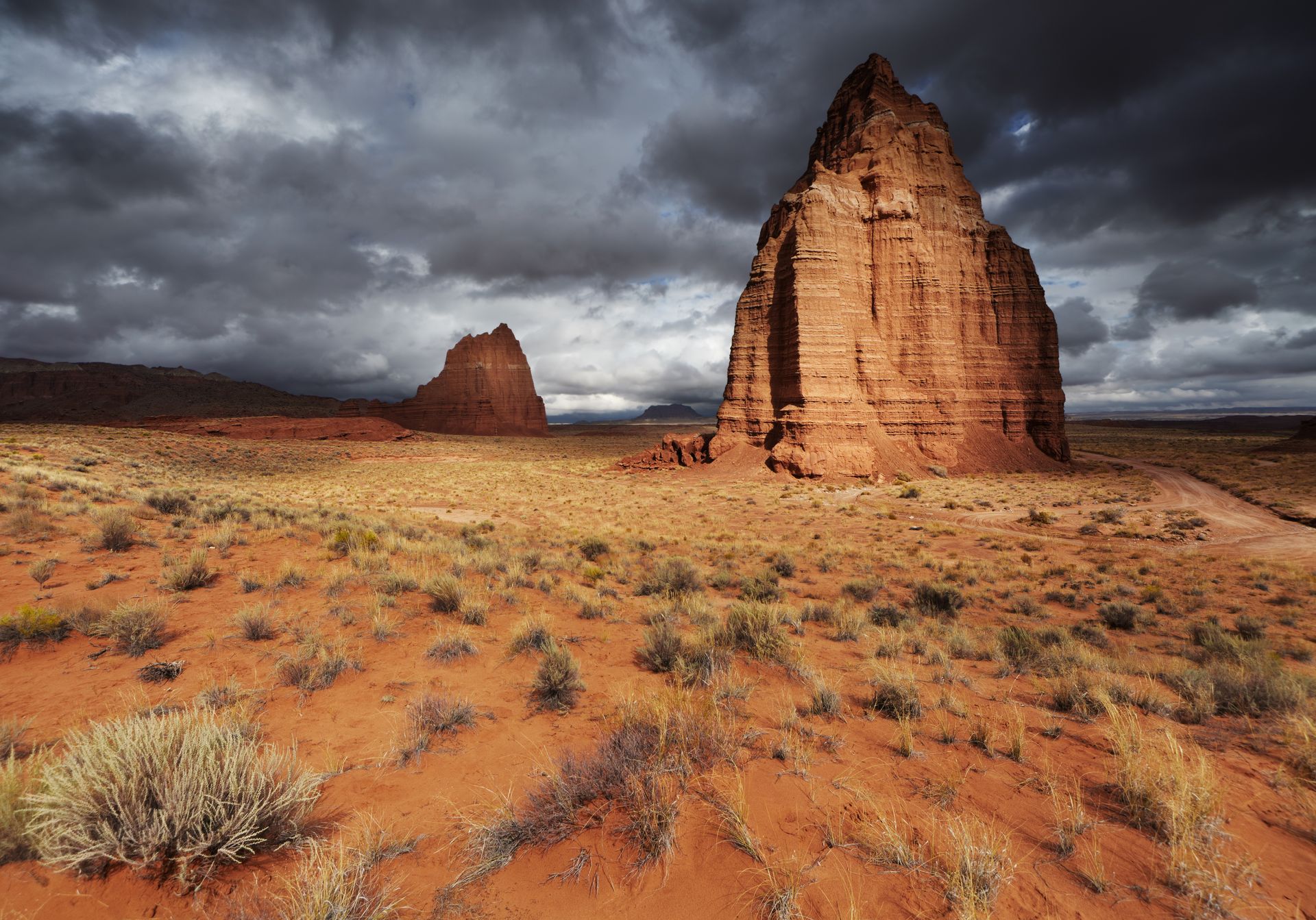 A large rock formation in the middle of a desert with a cloudy sky in the background.