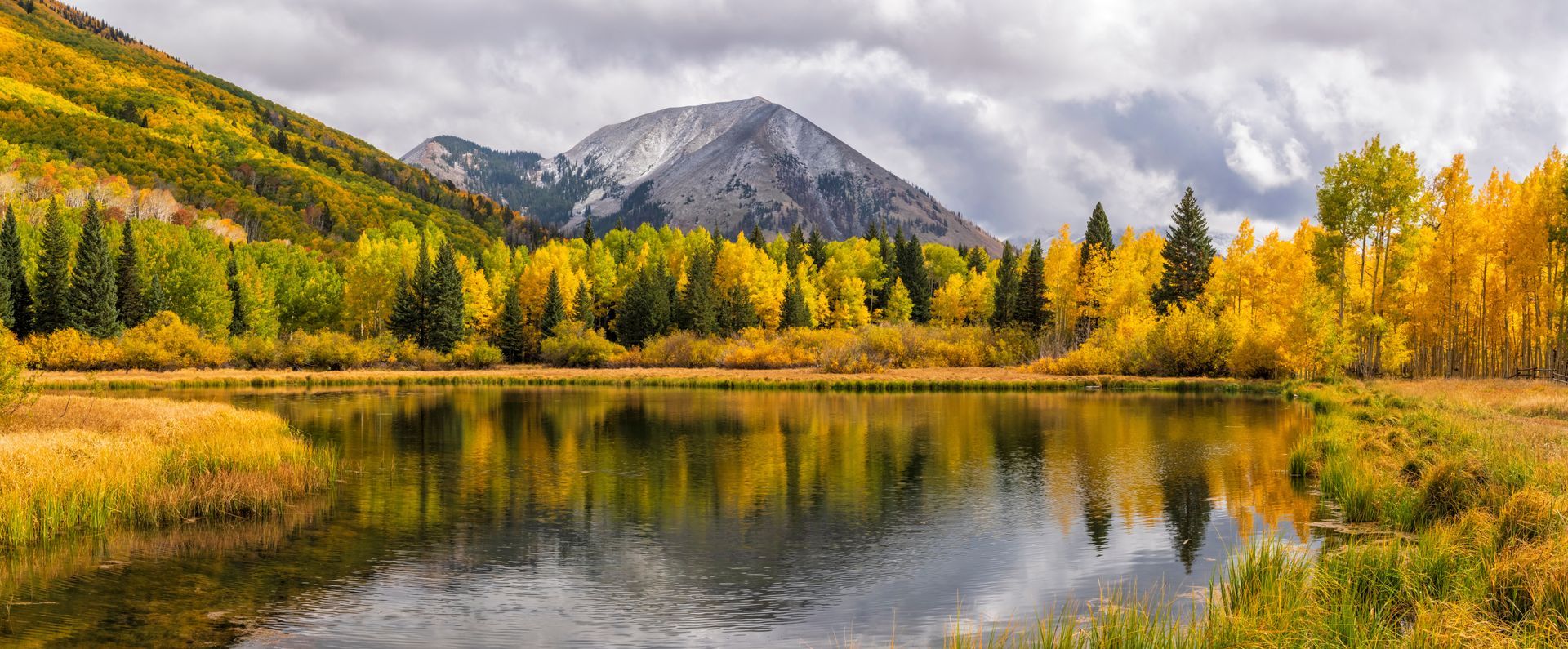 There is a lake in the middle of a forest with mountains in the background.