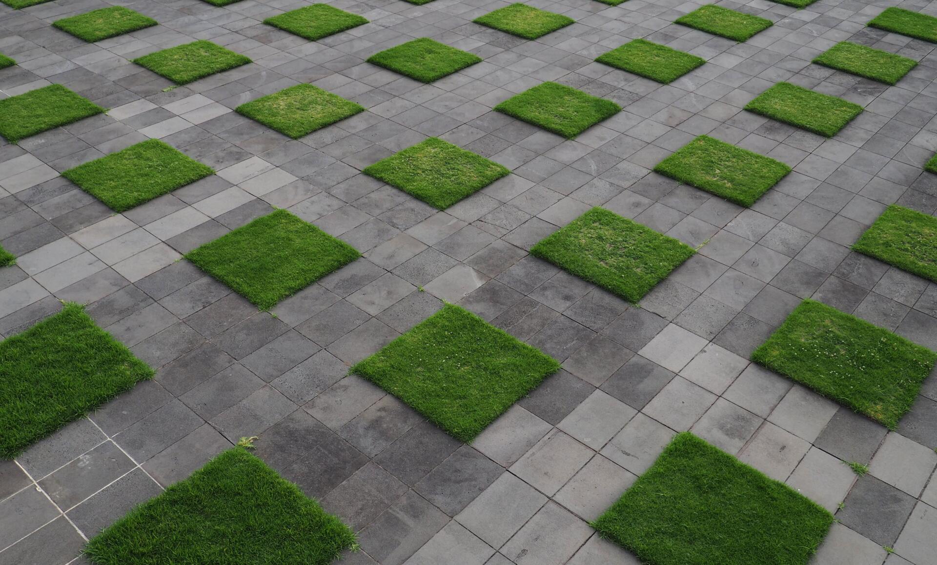 Synthetic grass pieces installed between concrete pavement