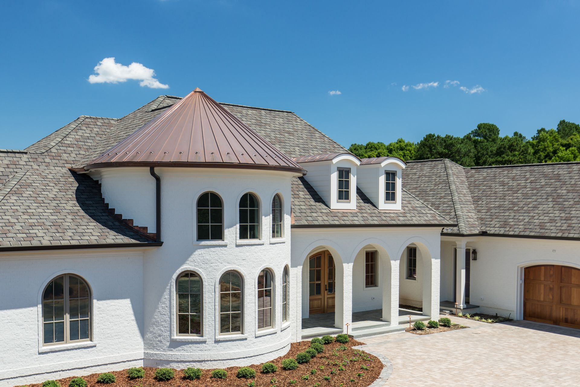A large white house with a copper roof and arched windows.