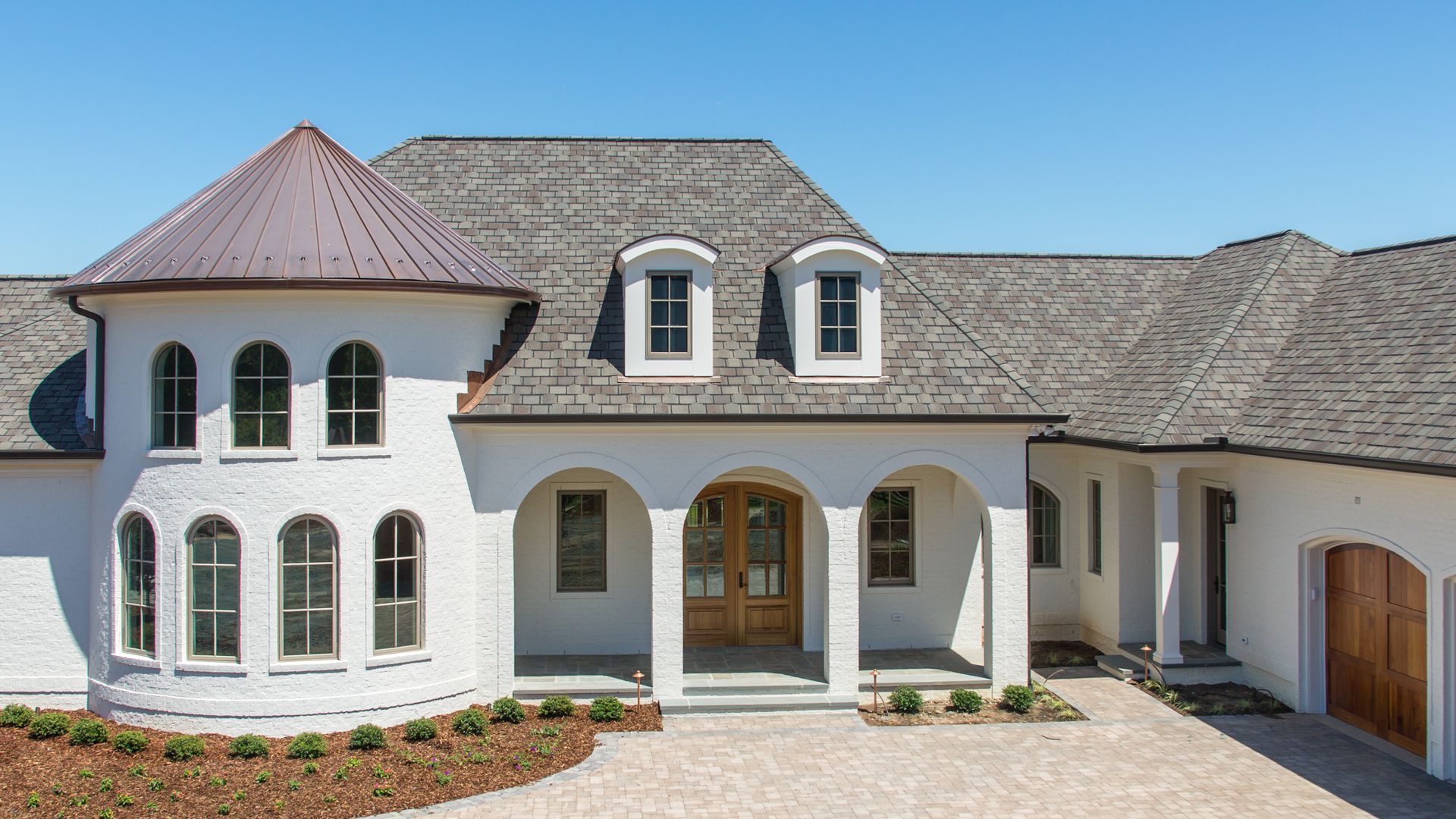 A large white house with a gray roof and arched windows.