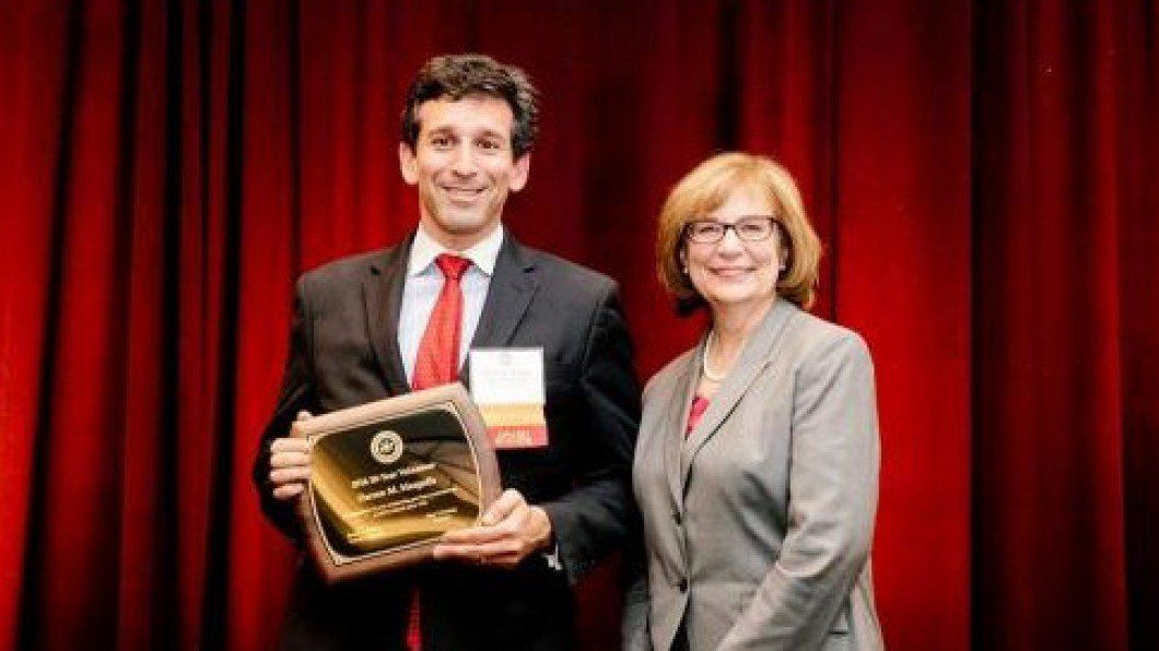 A man in a suit and tie is holding a plaque next to a woman in a suit.