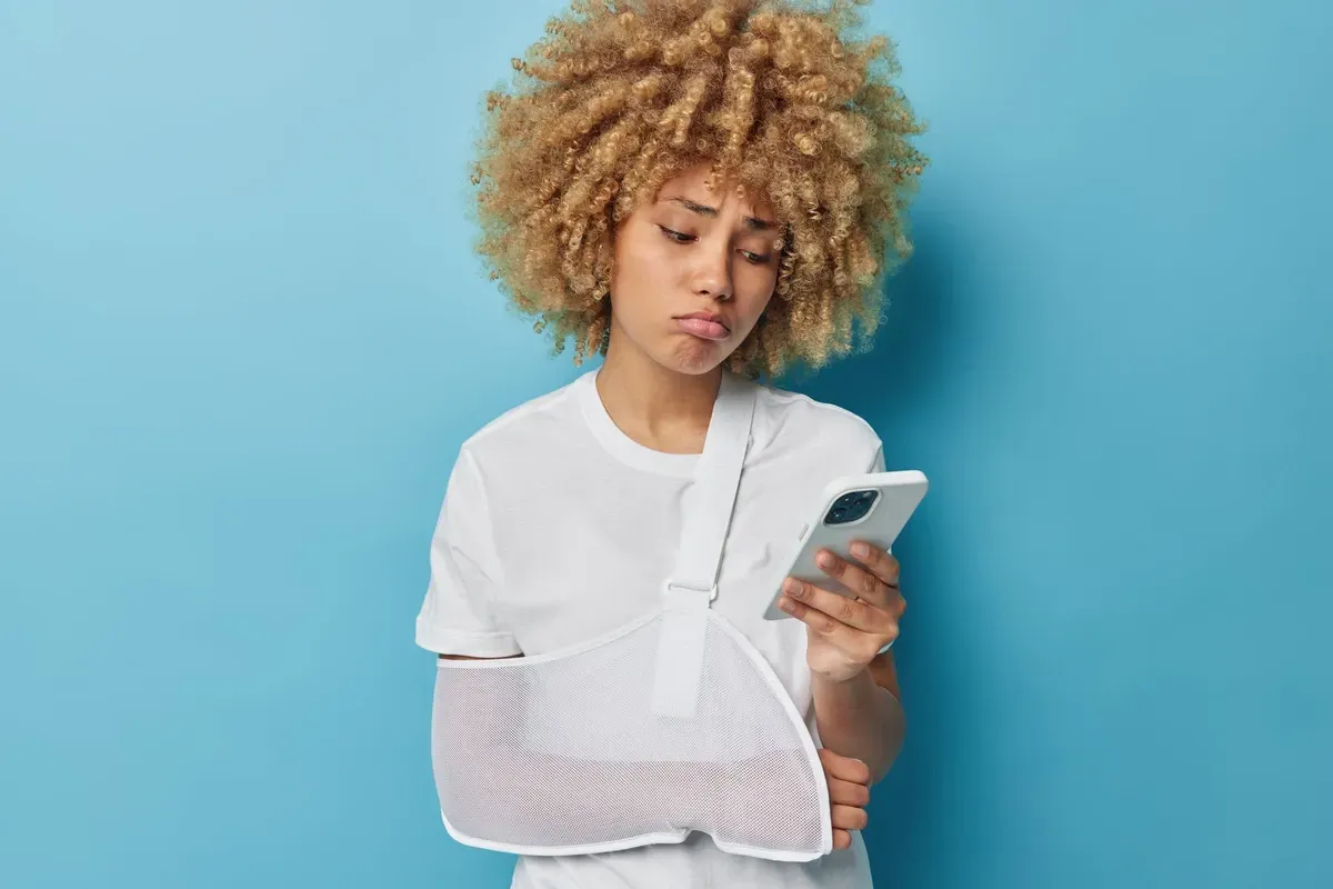 woman with arm in cast looks at mobile phone