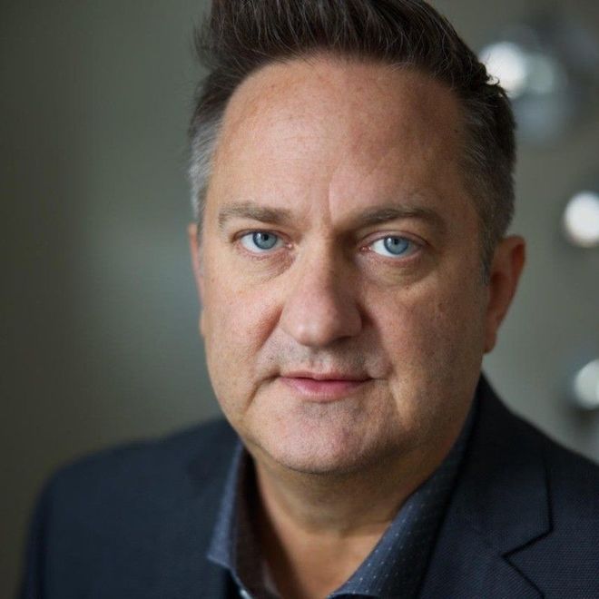 A man in a suit and blue shirt is looking at the camera.