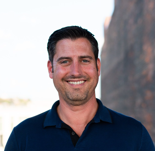 A man in a blue shirt is smiling for the camera