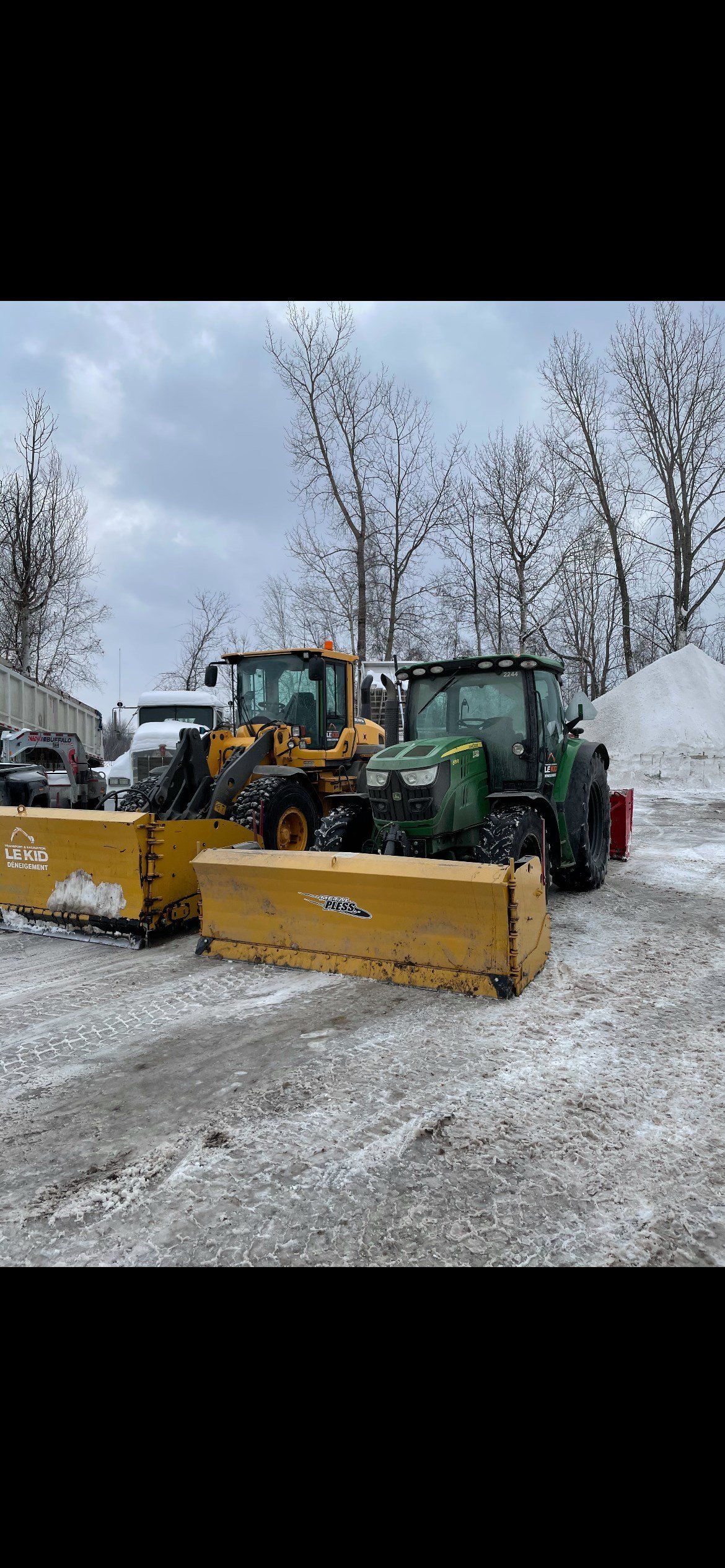 Deux chasse-neige sont garés l'un à côté de l'autre dans la neige.