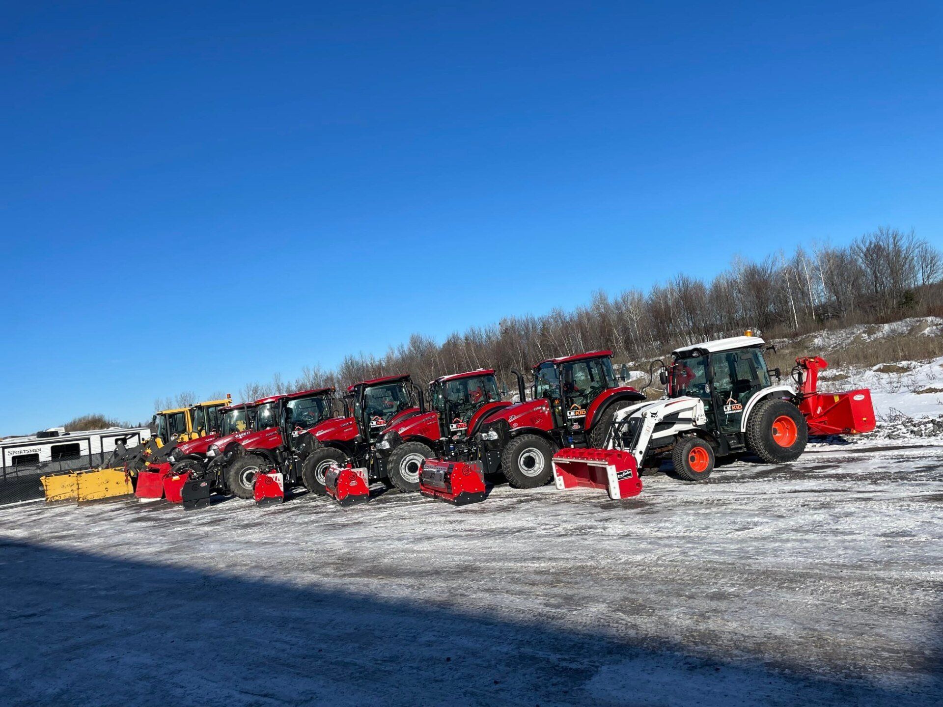 Une rangée de tracteurs est garée dans un champ enneigé.