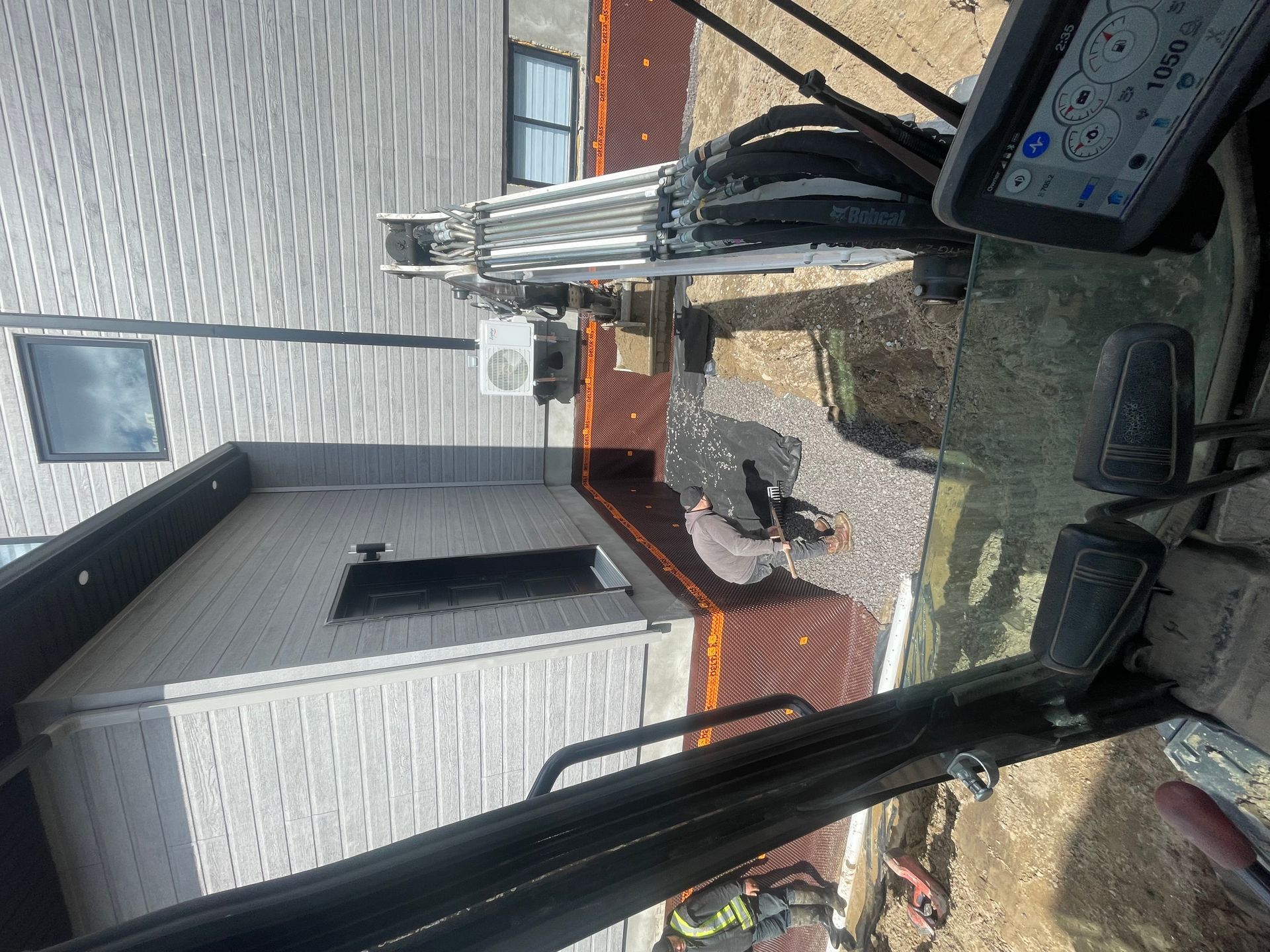 Un véhicule de construction est garé devant un bâtiment en briques.