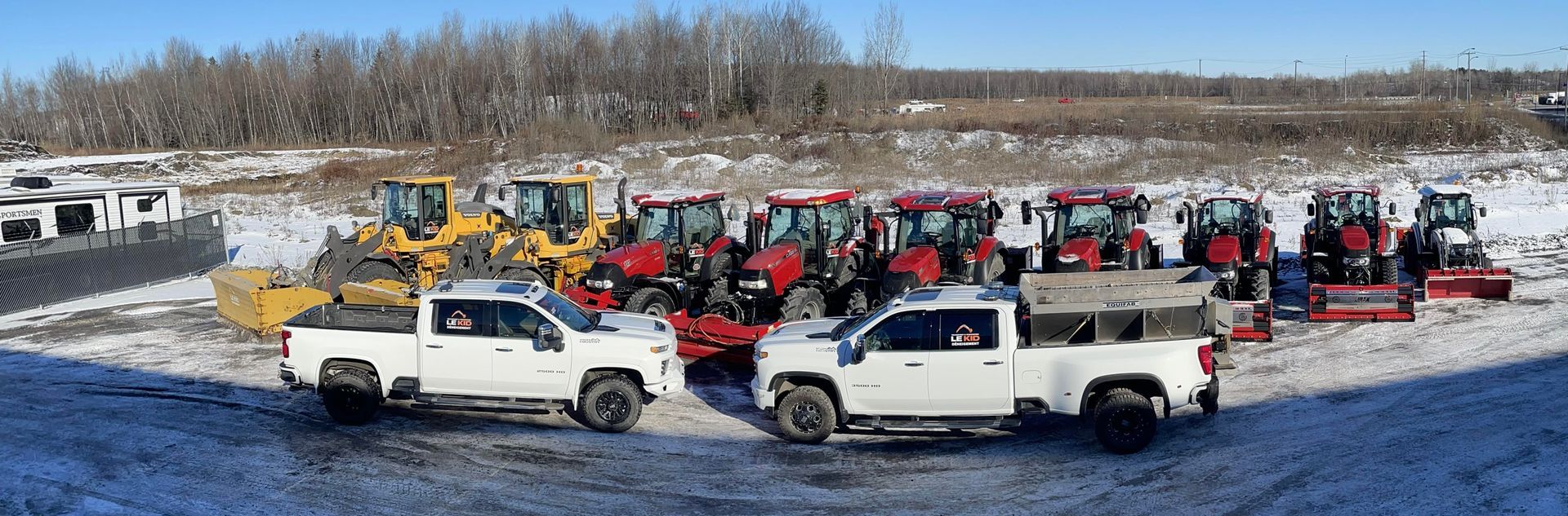 Un groupe de camions et de tracteurs sont garés dans un champ enneigé.