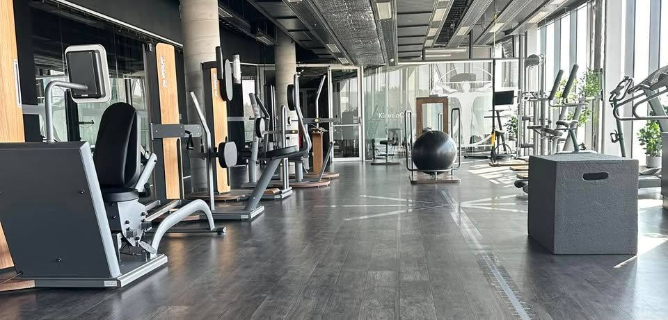 Didelė sporto salė, užpildyta daugybe treniruoklių.