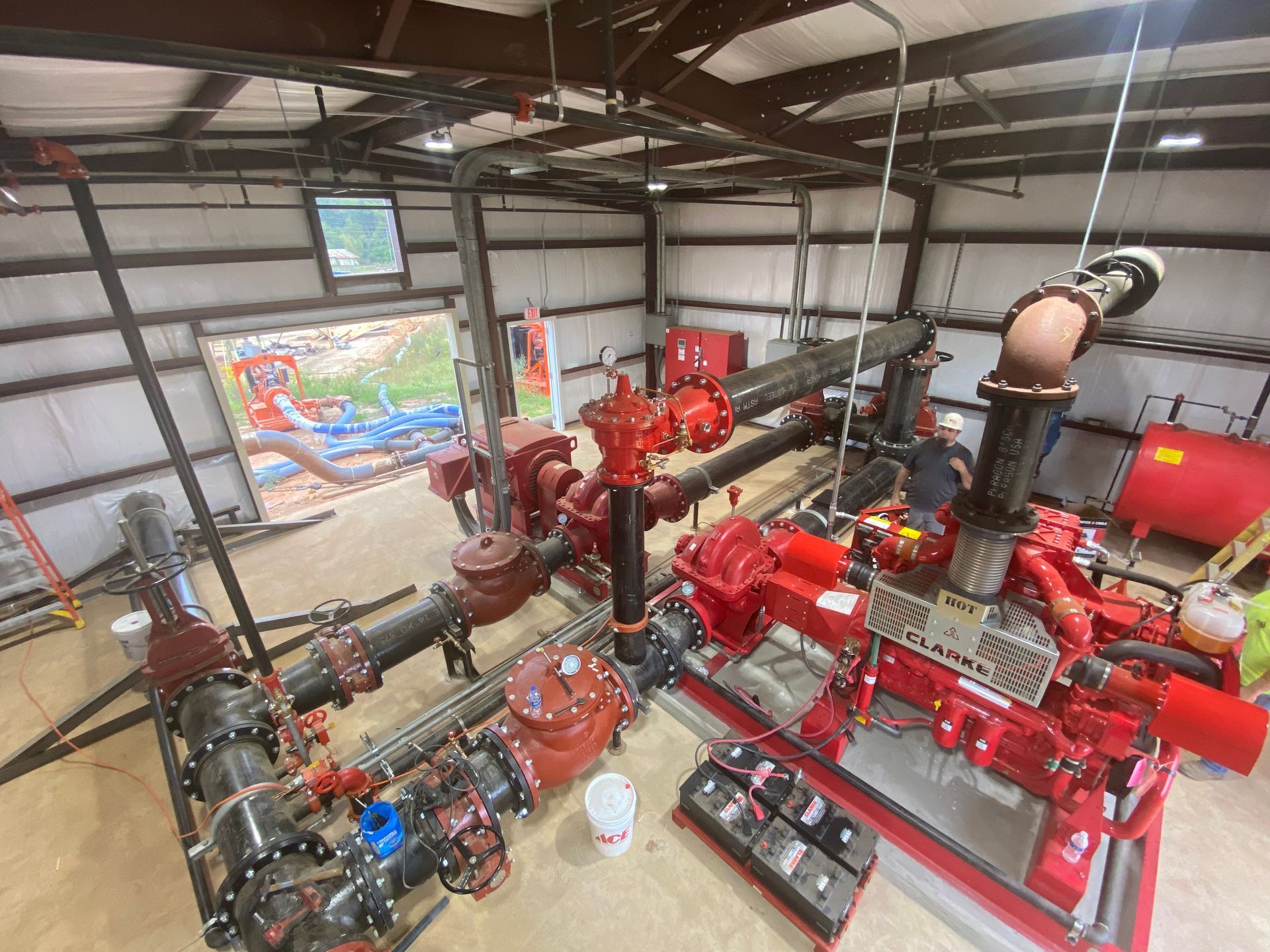 A man wearing a hard hat is working on a machine in a factory.