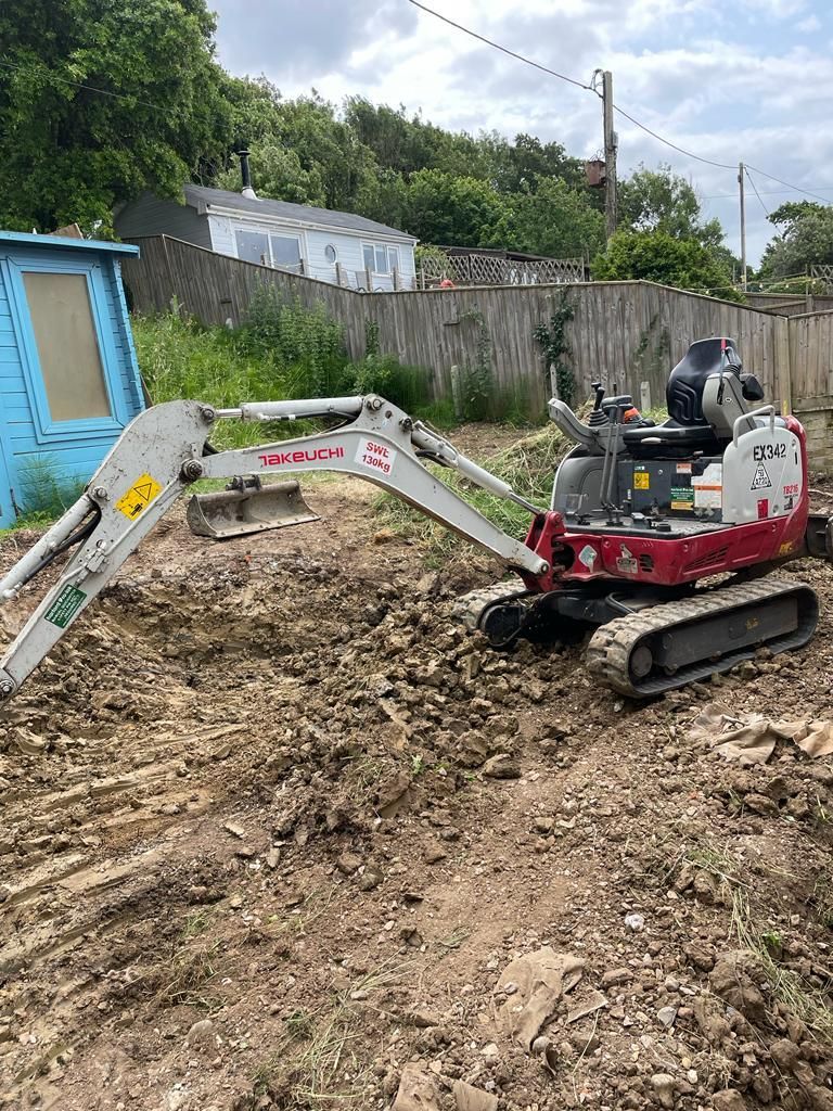 A small excavator is sitting on top of a pile of dirt. Isle of Wight