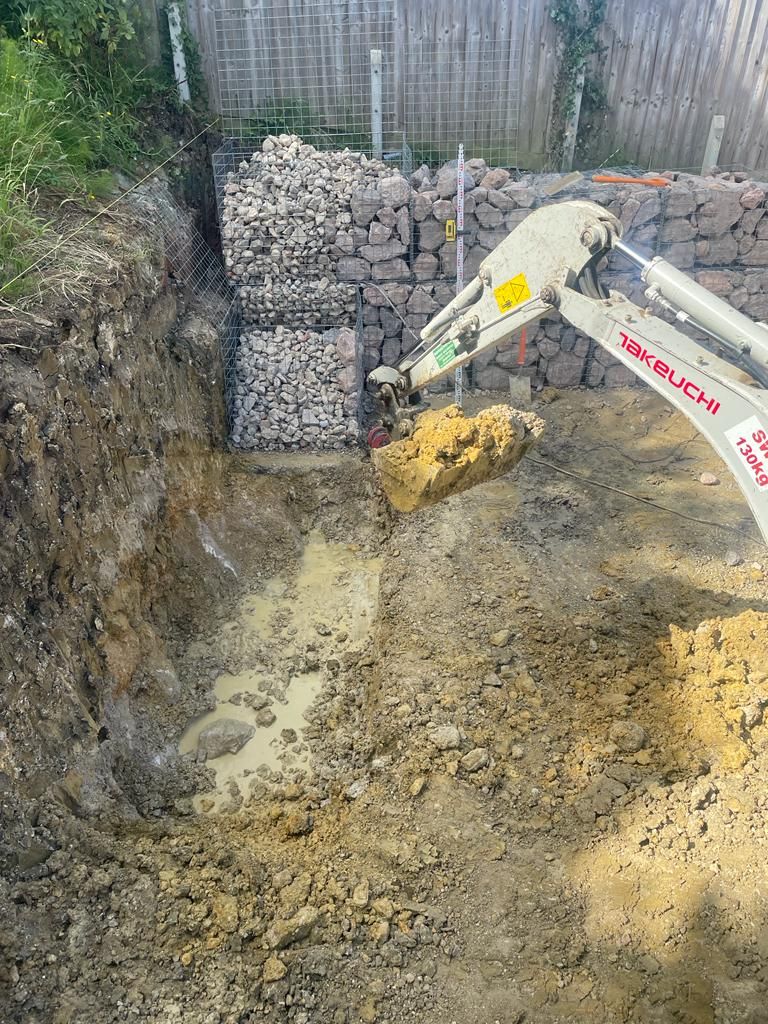 A small excavator is digging a hole in the ground. Isle of Wight
