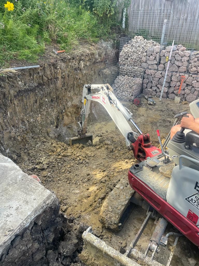 A small excavator is digging a hole in the ground. Isle of Wight