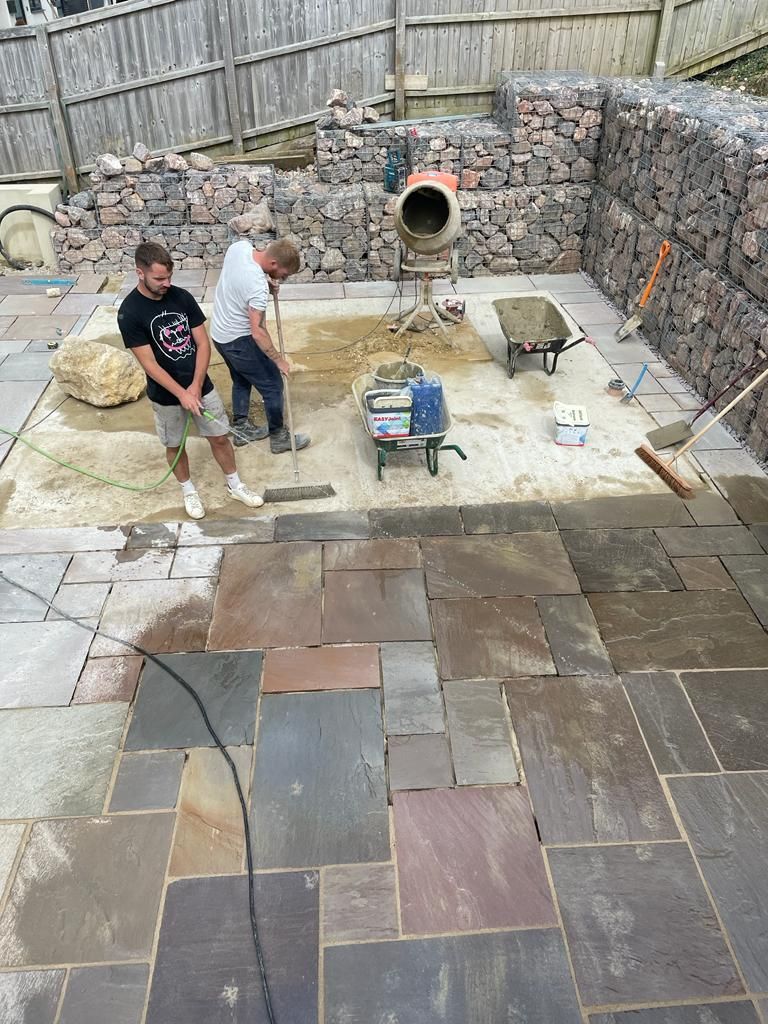 Two men are working on a patio in a backyard. Isle of Wight