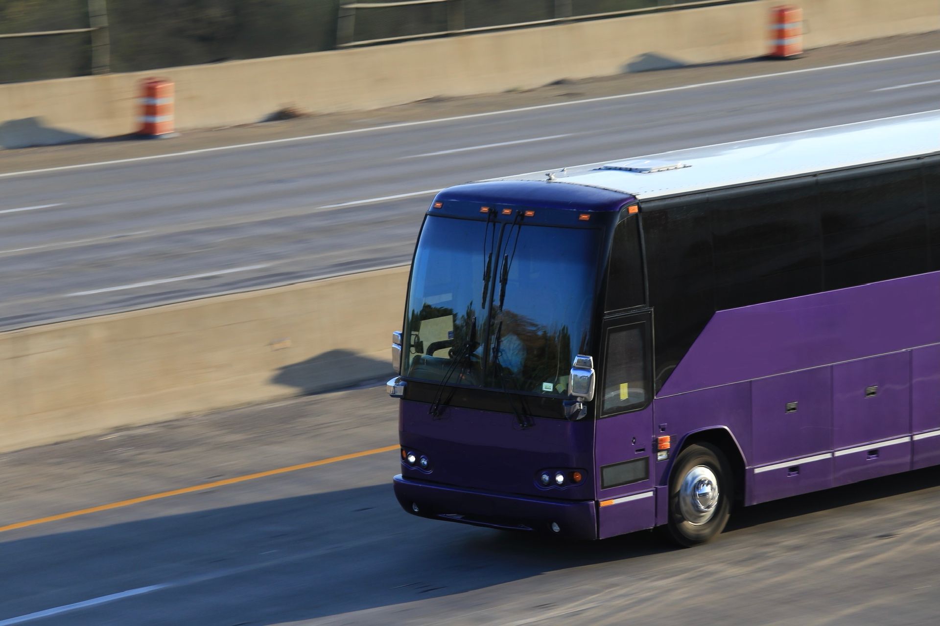 Purple bus driving down the road, ideal for bus charter services and vibrant travel experiences.