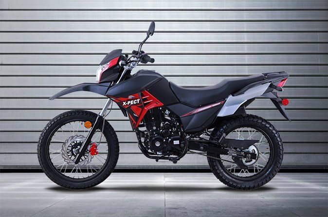 A red and black motorcycle is parked in front of a garage door.
