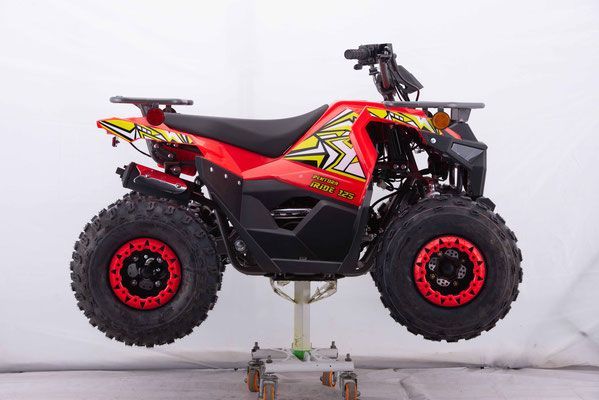 A red atv is sitting on a stand in front of a white wall.