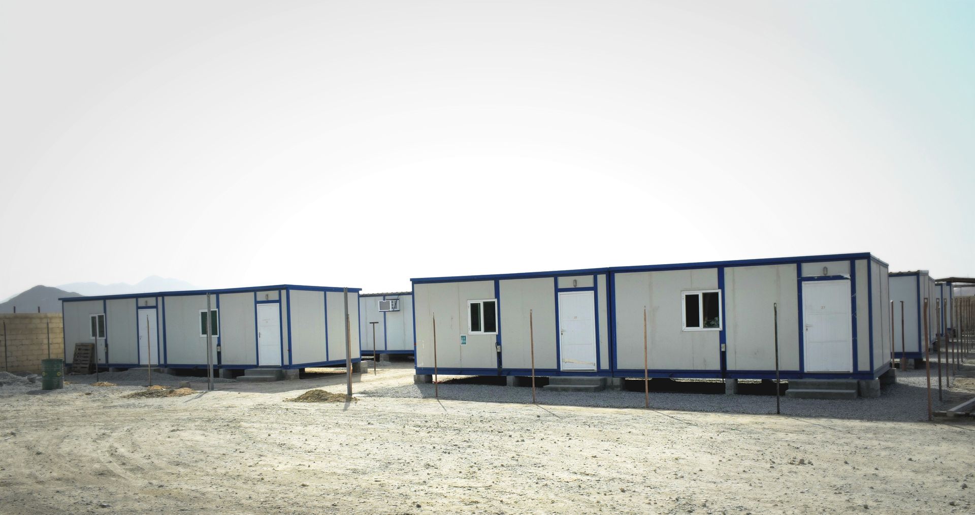 Multiple mobile storage containers arranged on a gravel lot, commonly used for temporary workspace or storage.