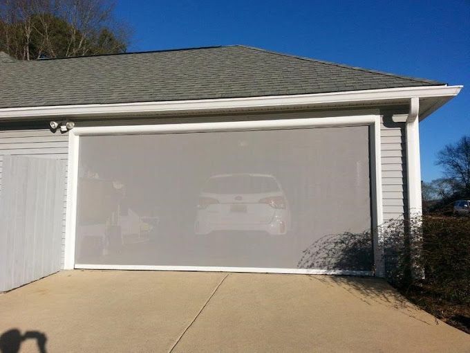 A car is parked in a garage with a screen door