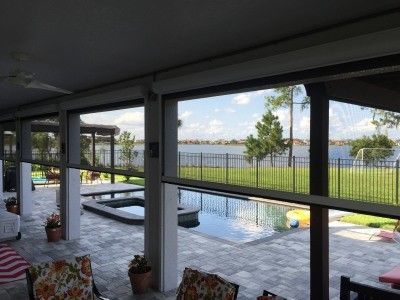 A screened in porch with a view of a pool and a lake.