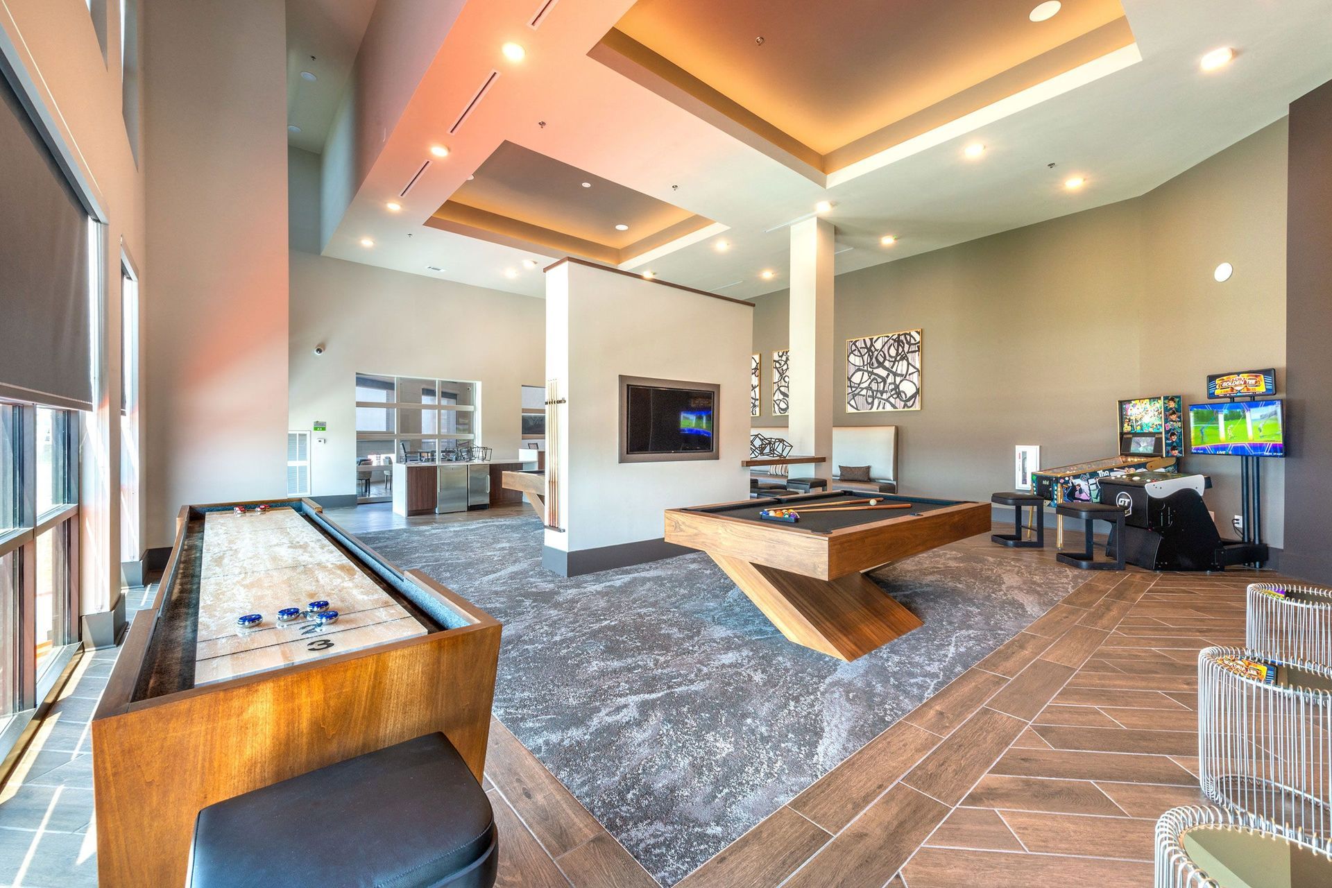 A large room with a pool table and a shuffleboard table.